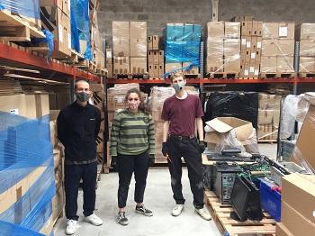 A group of three people in facemasks in a warehouse