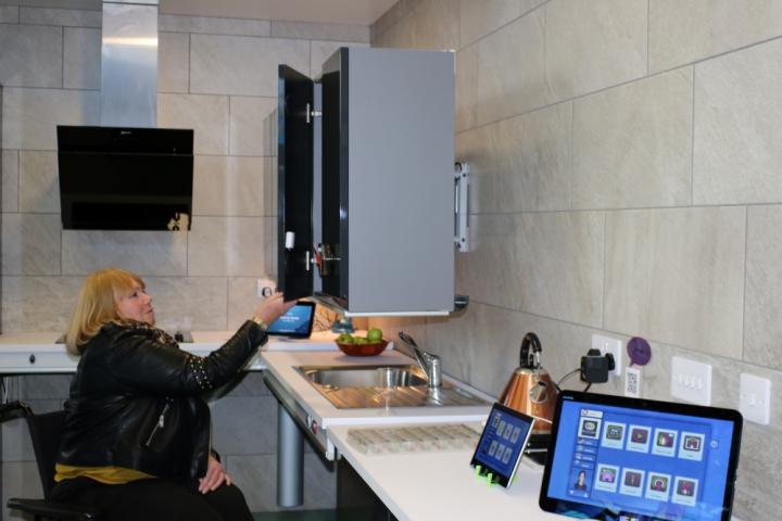 Photo of a woman in a mobility scooter using a kitchen with a smart meter.